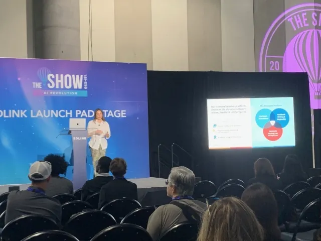 Packback team member presenting on stage at an education technology conference, speaking to an audience about learning and technology.